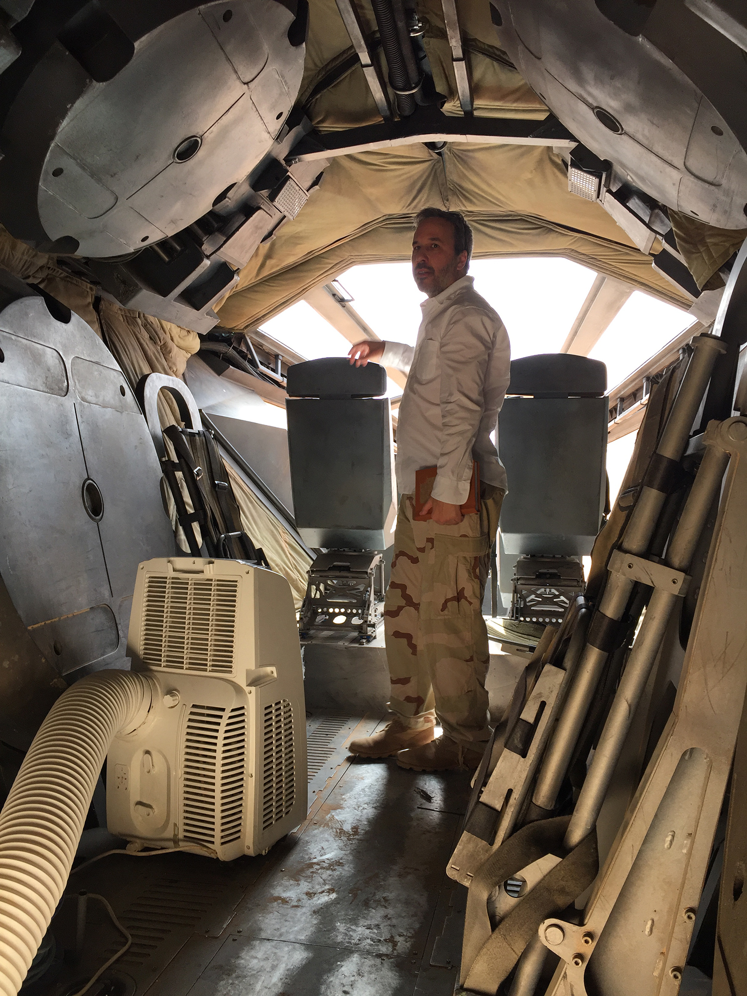 Photo of director Denis Villeneuve inside of an ornithopther on the set of the 'Dune: Part One' movie.