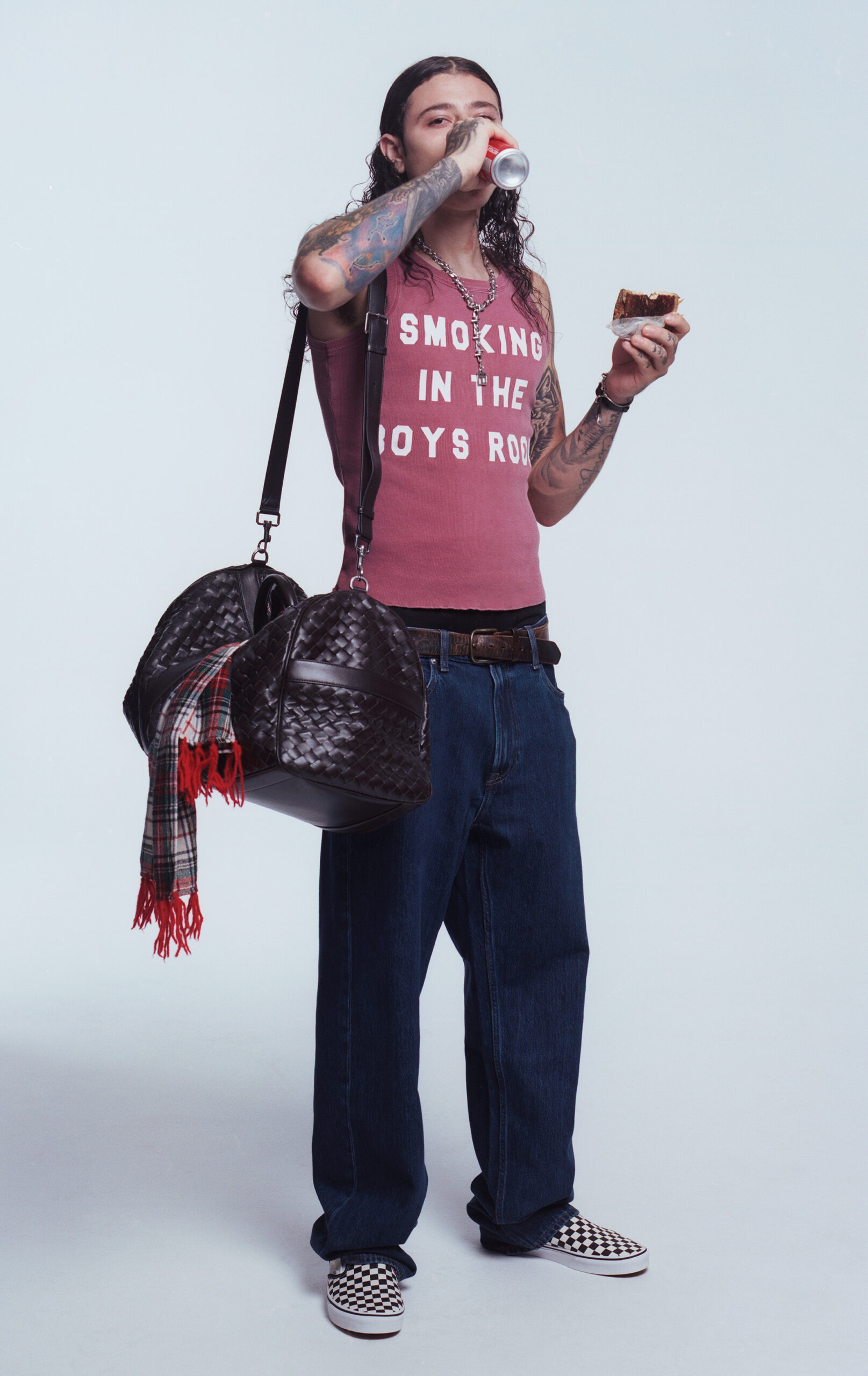 Jay Guapo standing up with a sandwich in one hand and a drink in the other.