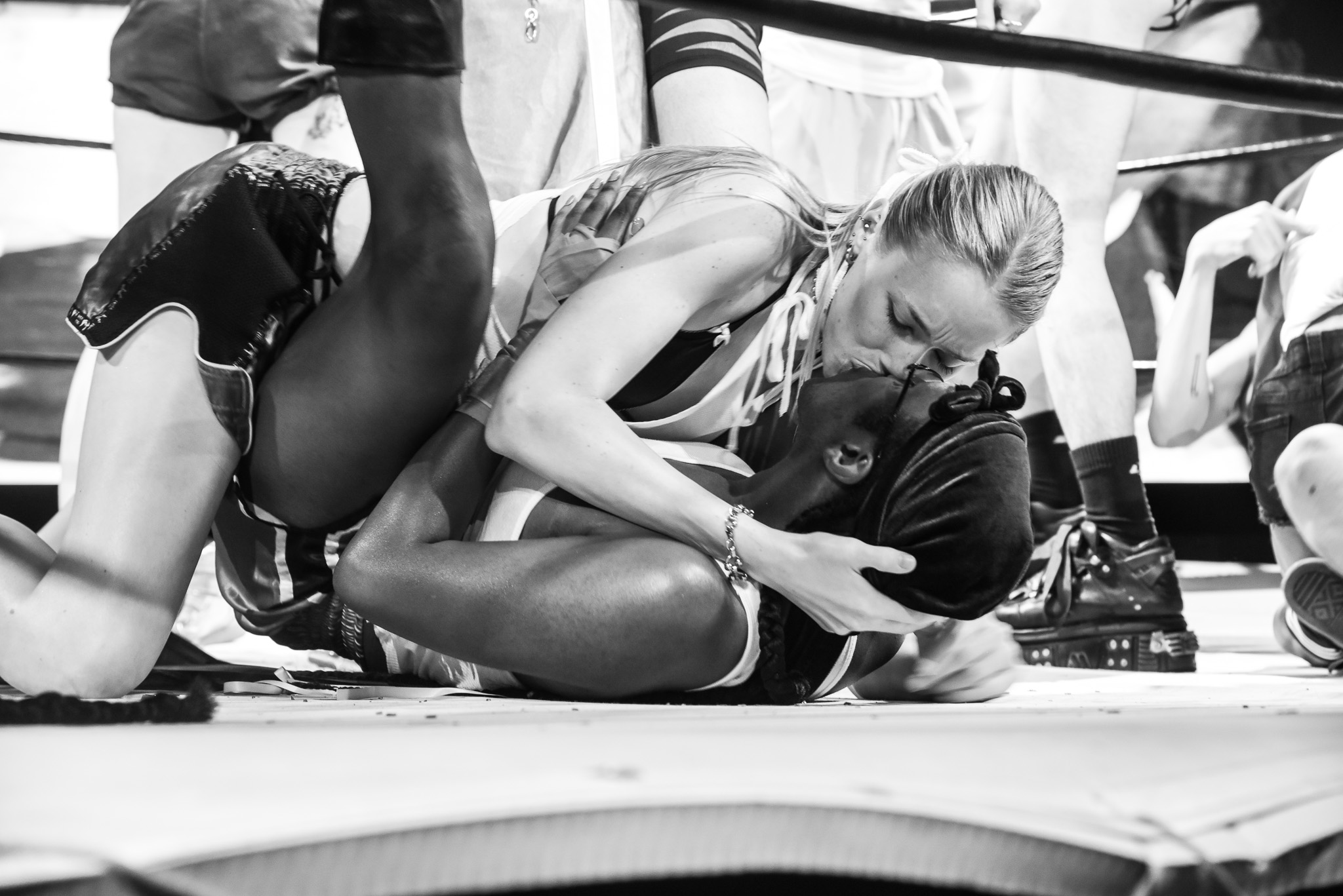 Two contestants makeout on the mat of a boxing ring.