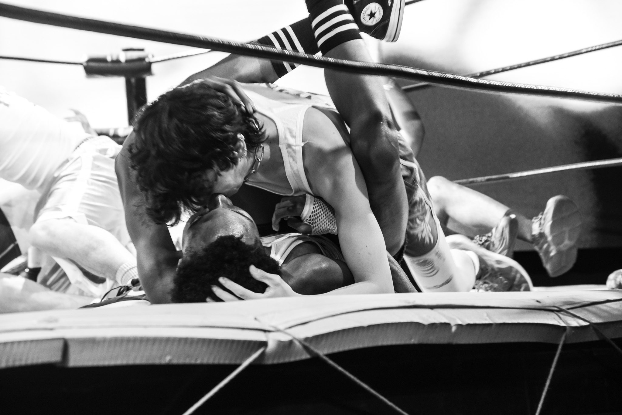 A black and white photo of two contestants making out on the mat of a boxing ring.