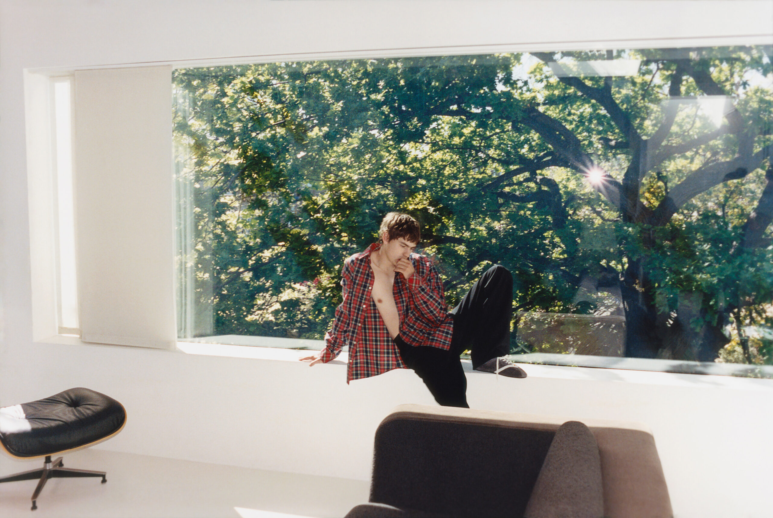 Spike Fearn sits in on the window sill deep in thought with one leg propped up and his hand in this mouth