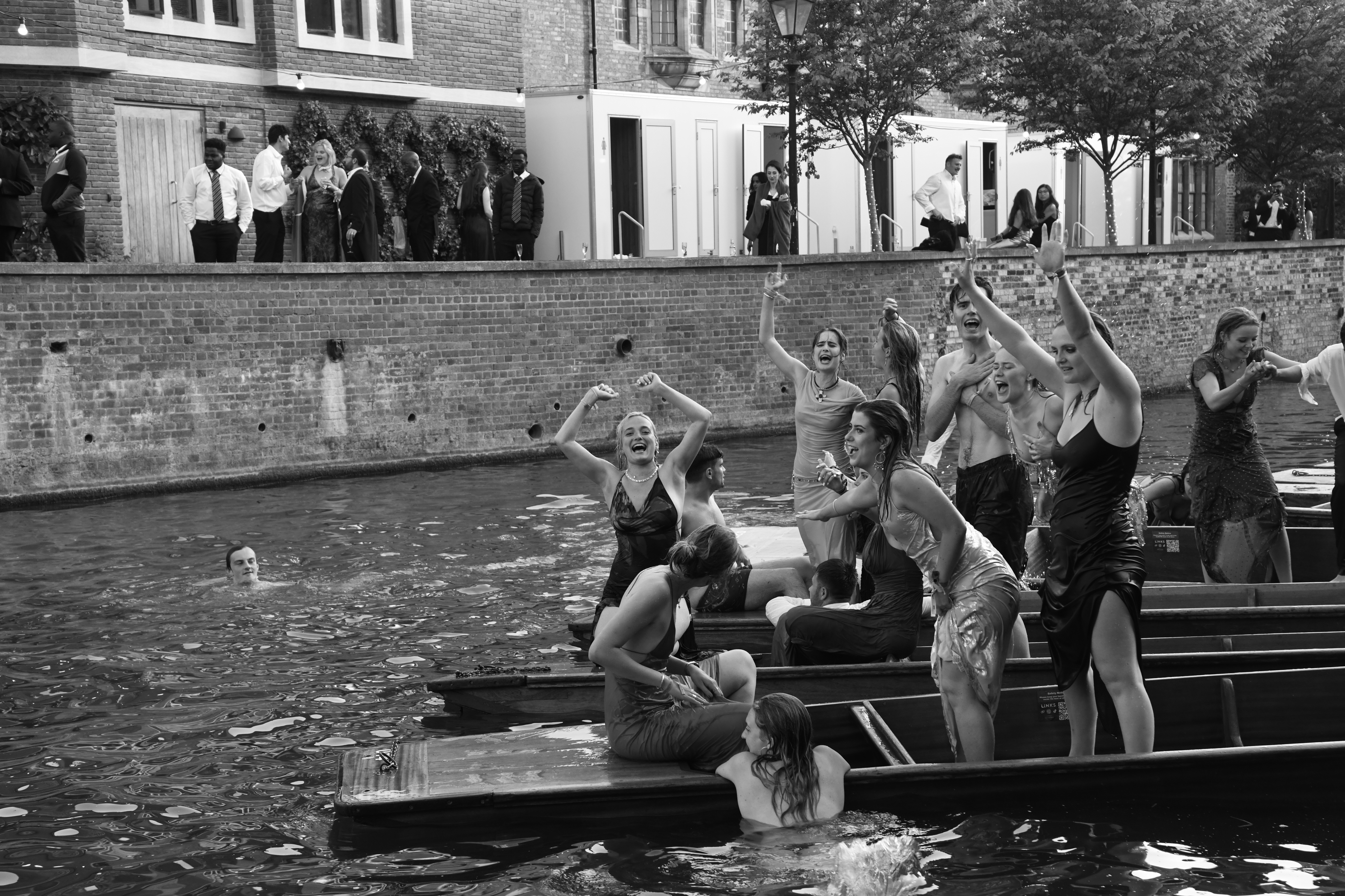 Students drenched in water cheer on rowing boats at Cambridge May Ball