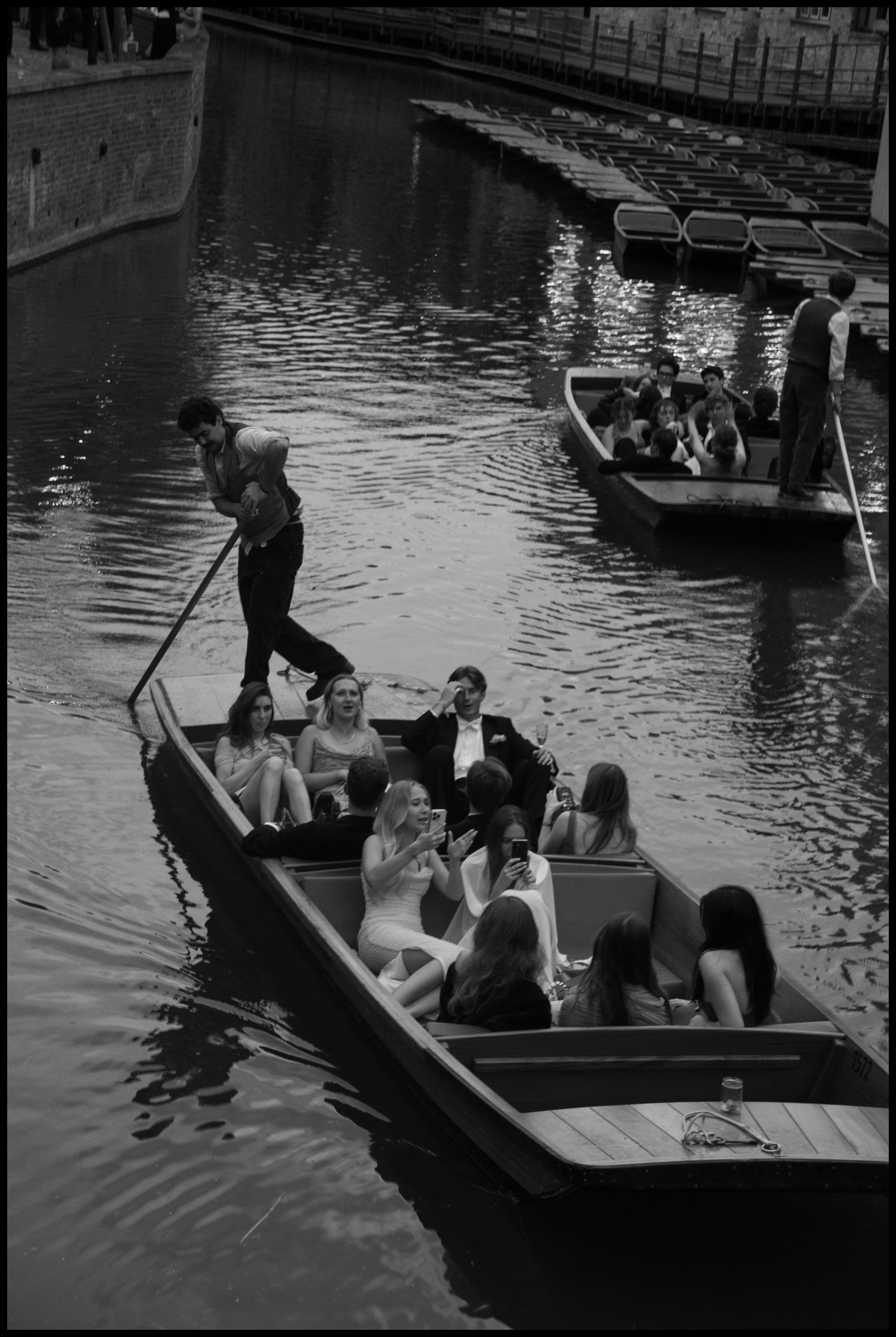 Students sit on rowing boat holding iPhones at Cambridge May Ball