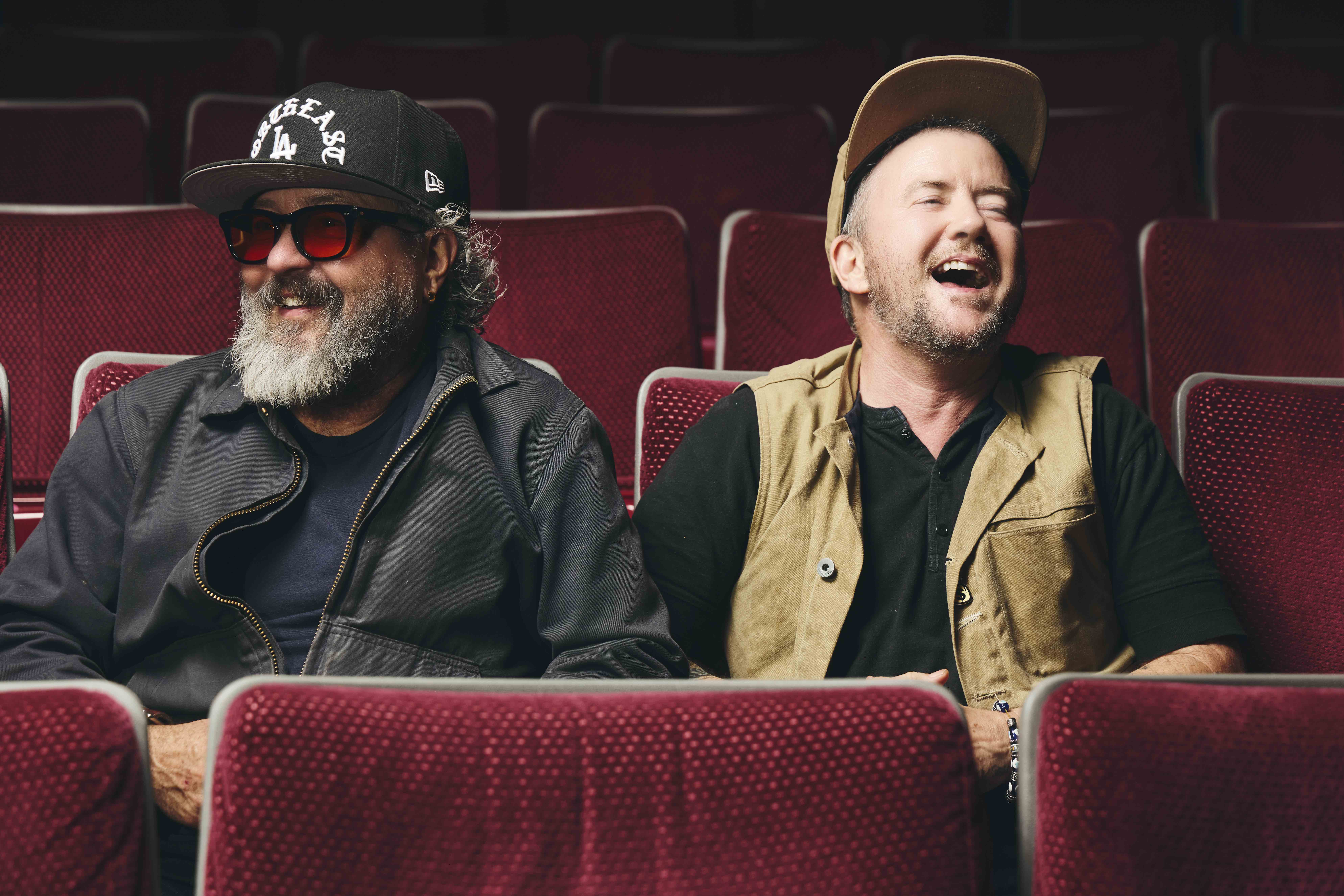 Harry Dodge and Silas Howard laughing while sitting in red seats at a theater