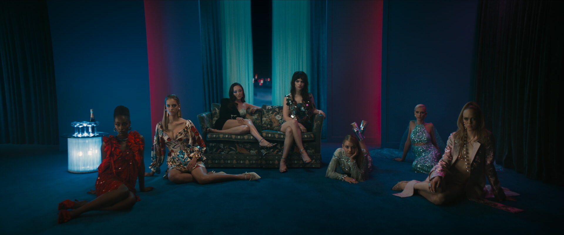 Sophie Thatcher and Havana Rose Liu sit on a couch surrounded by other elegantly dressed women in Her Private Hell. 