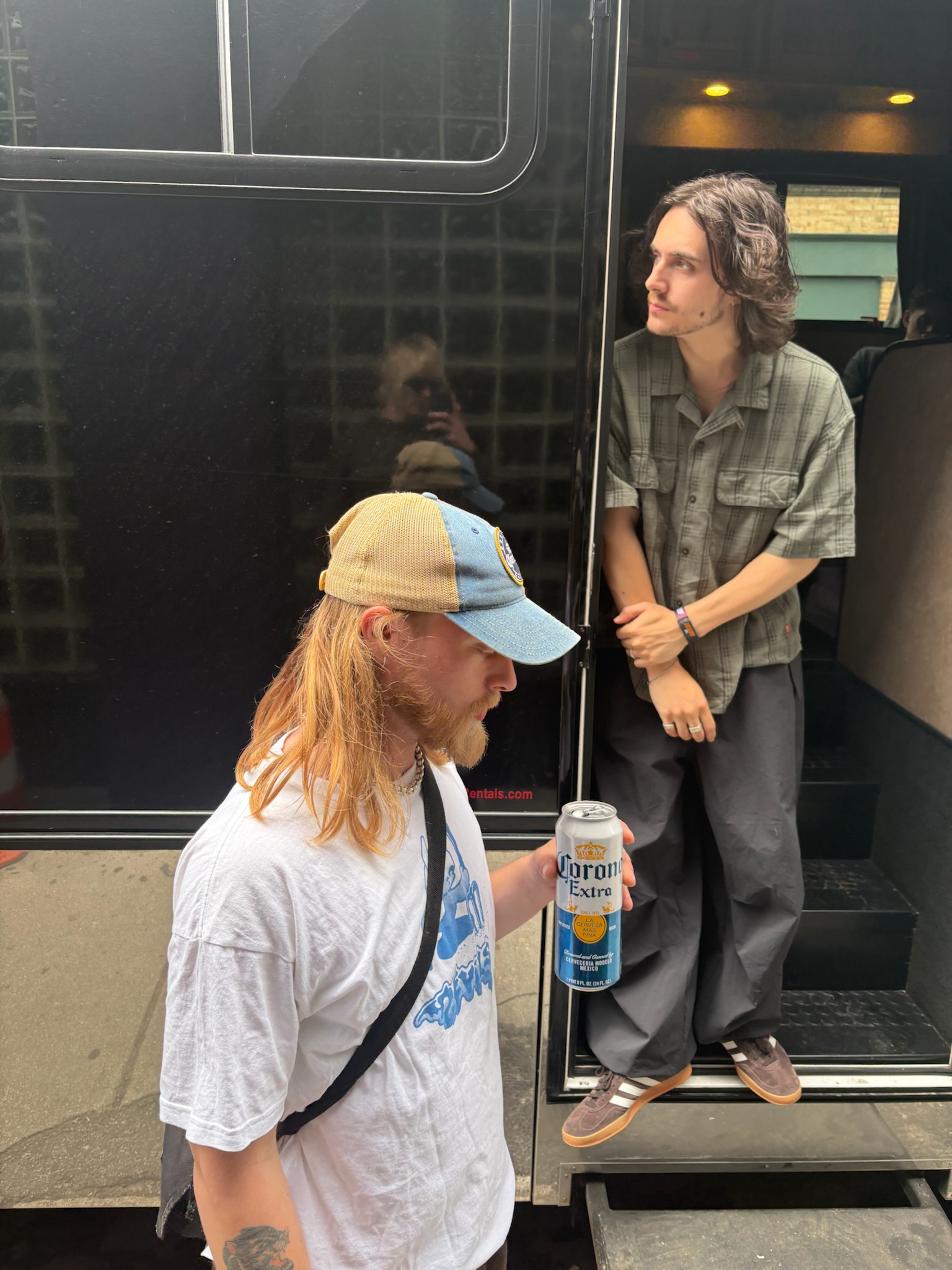 Ben Taylor of Villanelle stands at the open door of his tour bus looking outside to the left.