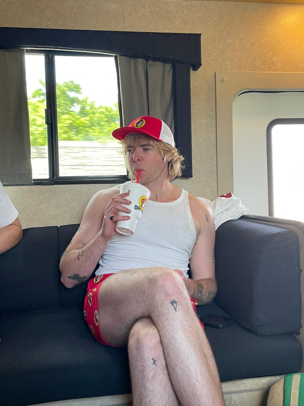 Jack Schiavo of Villanelle sips on his drink from Buc-ee's on the tour bus couch.