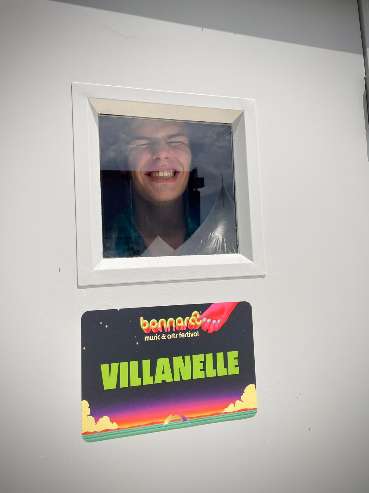 A boy smiles from inside the window of a Bonnaroo tour bus.