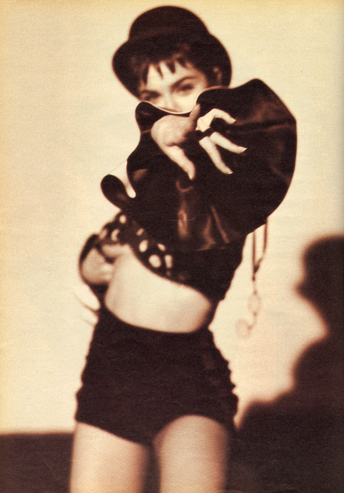 Madonna points at camera wearing top hat.