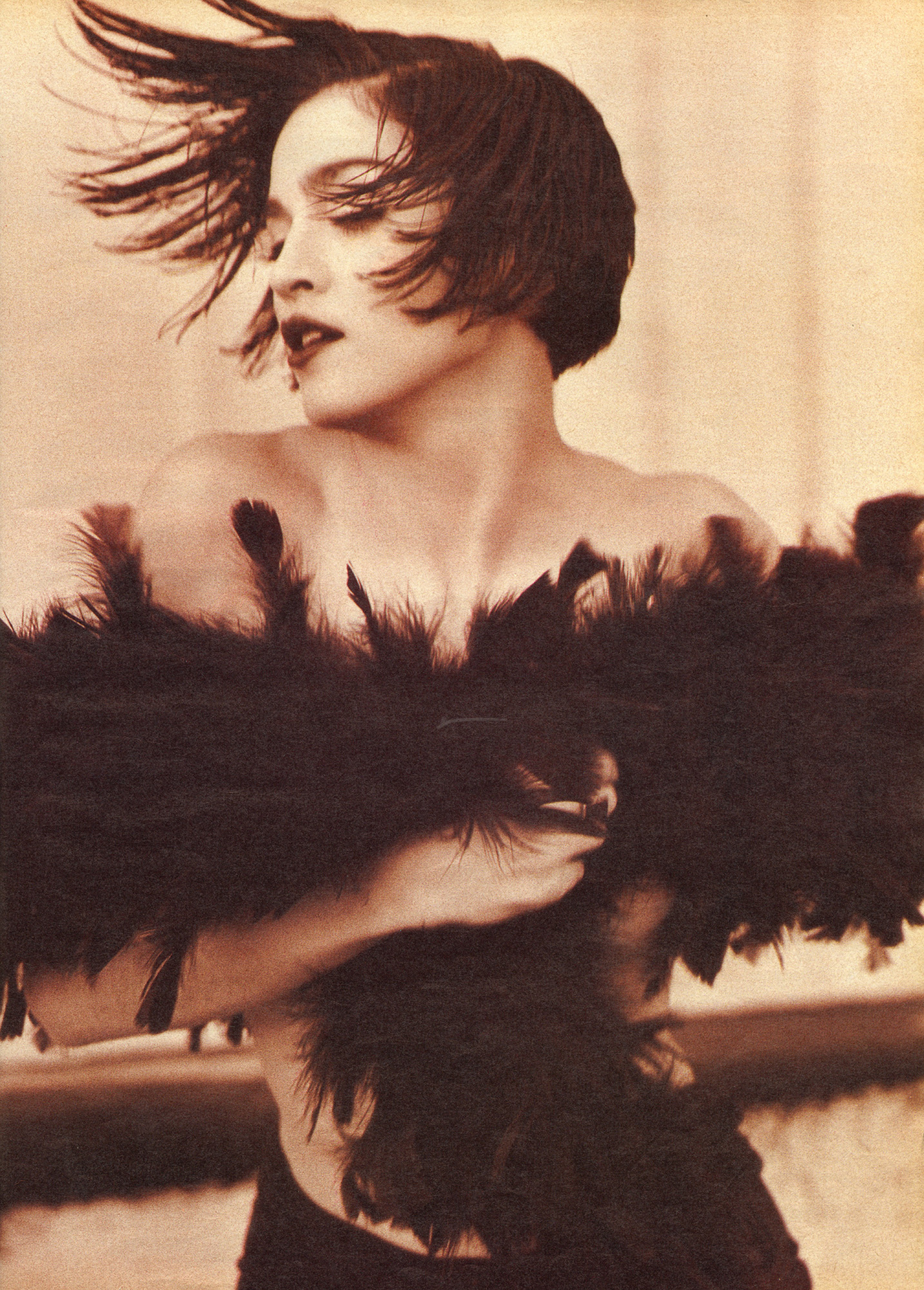 Madonna twirling dressed in feathers, her hair sticks up.