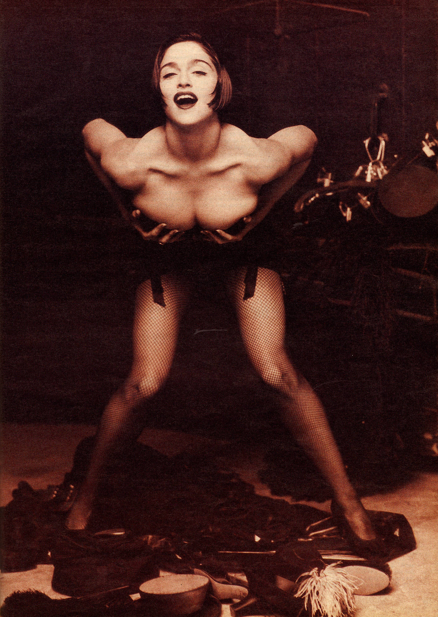 Madonna bends down and holds breasts.