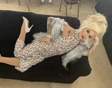 Katya Zamolodchikova reclining on a couch in a silver dress